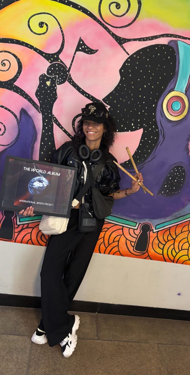 Frau in schwarzem Outfit, umgeben von lila und blauen Lichtern, in einem stilvollen Raum.